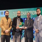 Group of four men at a Tech Champions award ceremony holding a trophy, showcasing recognition in technology innovation.